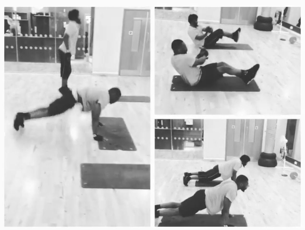 Coach Spartan coaching a client through floor work and squats in a commercial gym